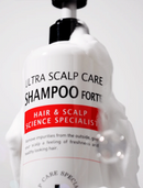 A white pump bottle of Ultra Scalp Care Shampoo Forte covered in thick white foam, with a black pump and a red label band reading 'Hair & Scalp Science Specialist'.