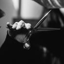 Mizutani ACRO Crossover CR-2 scissors held in an expert's hand, demonstrating the crossover handling style for barbers and stylists.